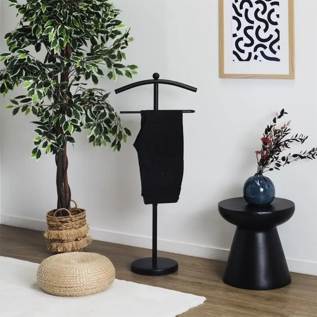 Zwarte kledingstandaard van WDMT naast bed in moderne slaapkamer